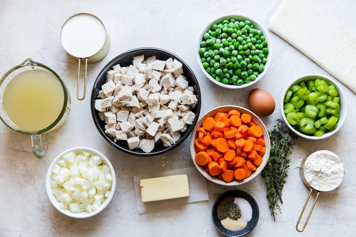 ingredients laid out for Skillet Chicken Pot Pie carrots, onions, chicken stock, milk, celery, peas, butter, flour