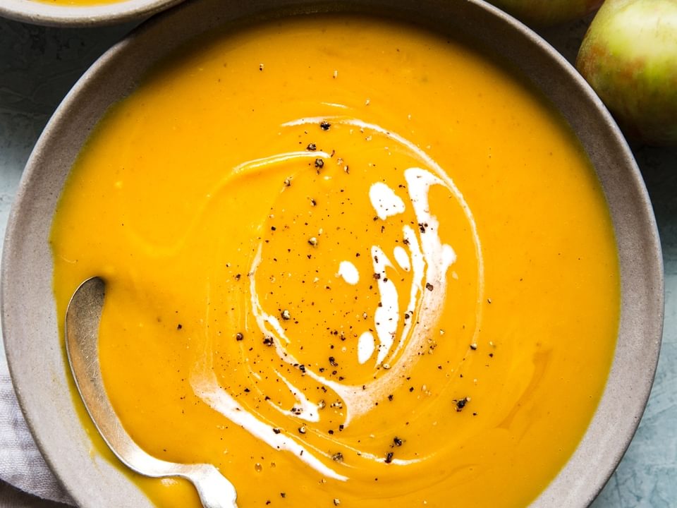 two bowls of slow cooker butternut squash apple soup with a coconut milk drizzle on top