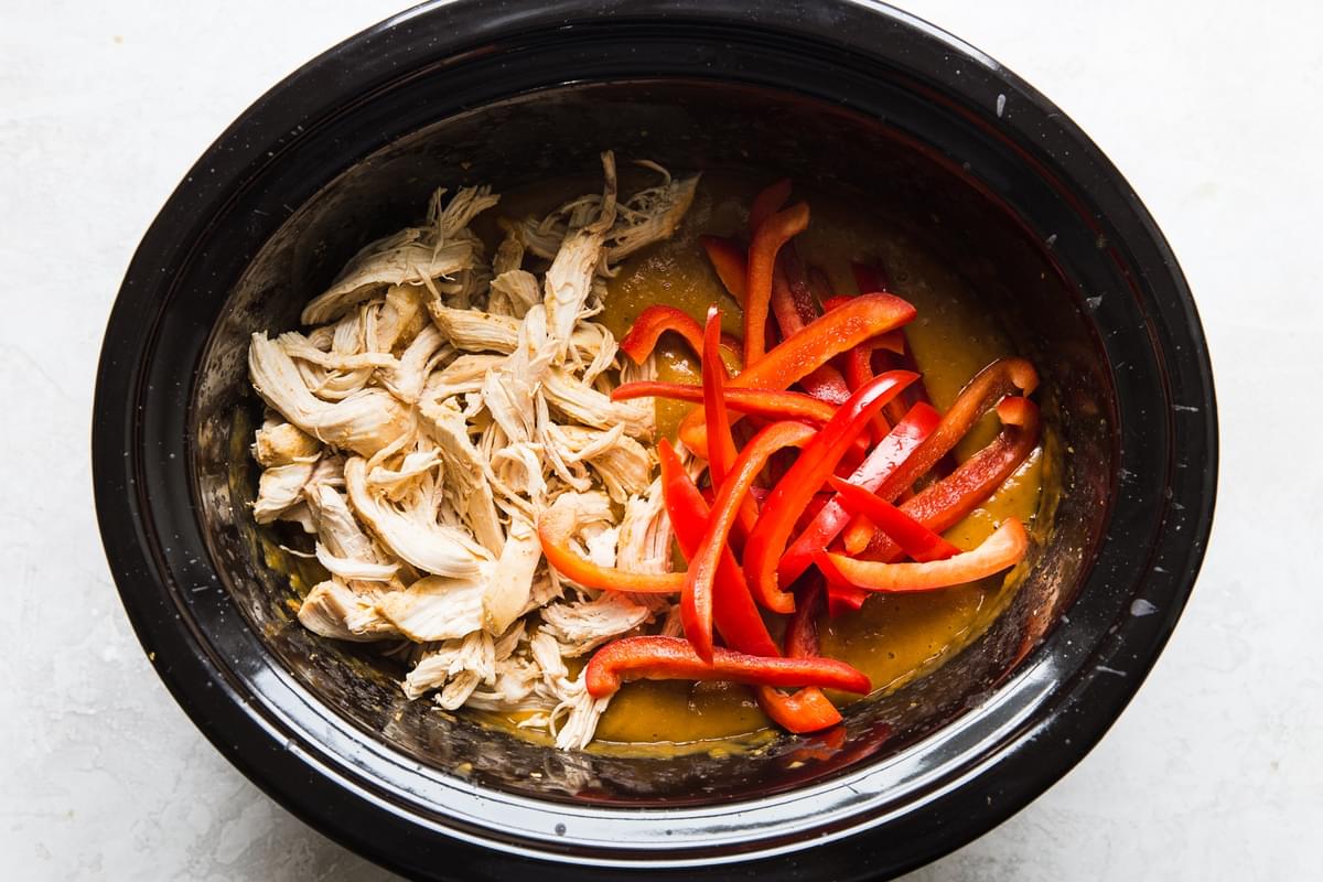pumpkin curry with shredded chicken and raw red bell peppers in a slow cooker