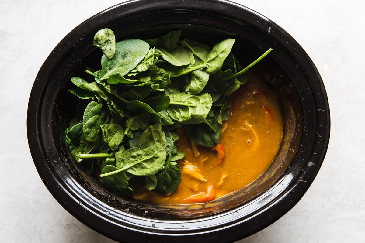 chicken pumpkin curry topped with fresh spinach in slow cooker