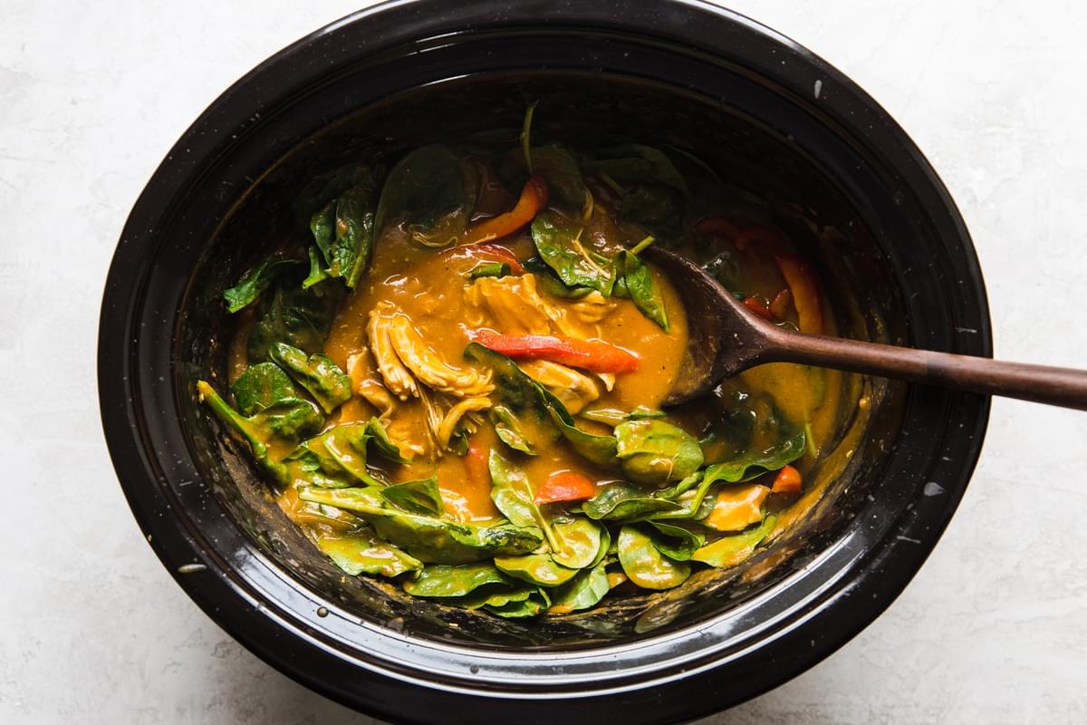 slow cooker pumpkin curry in a crock pot with shredded chicken, bell peppers and fresh baby spinach