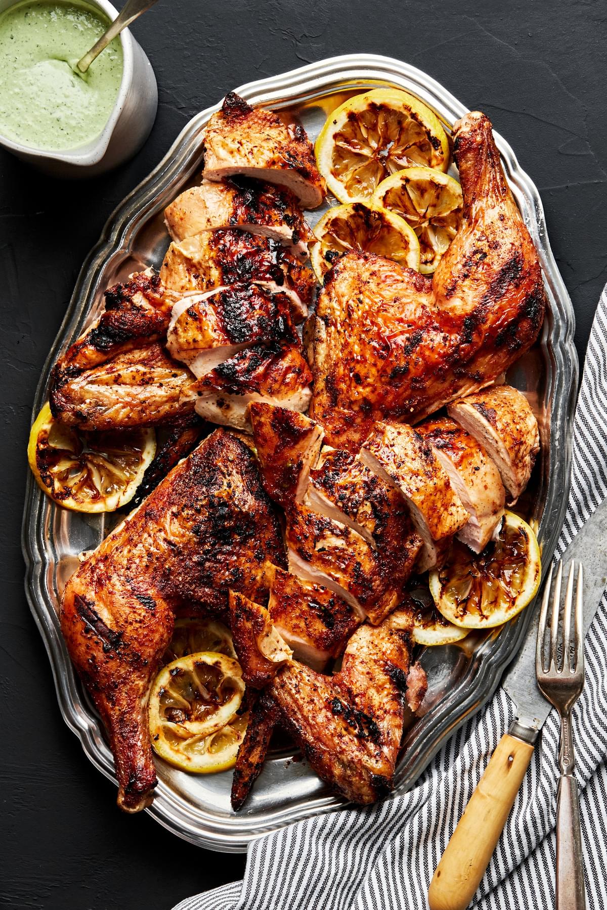 spatchcocked grilled chicken on a serving platter seasoned with brown sugar, paprika, garlic powder, pepper and salt