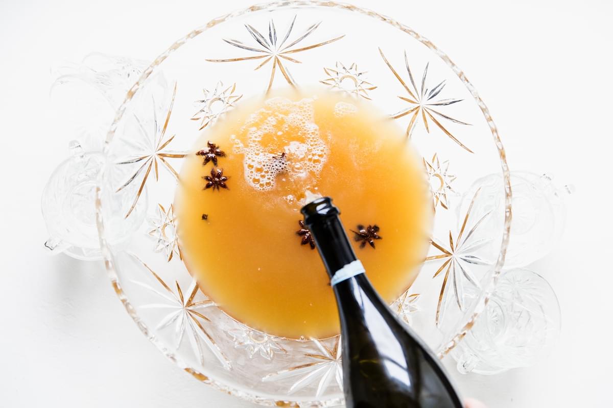 hand pouring champaign in a punch bowl