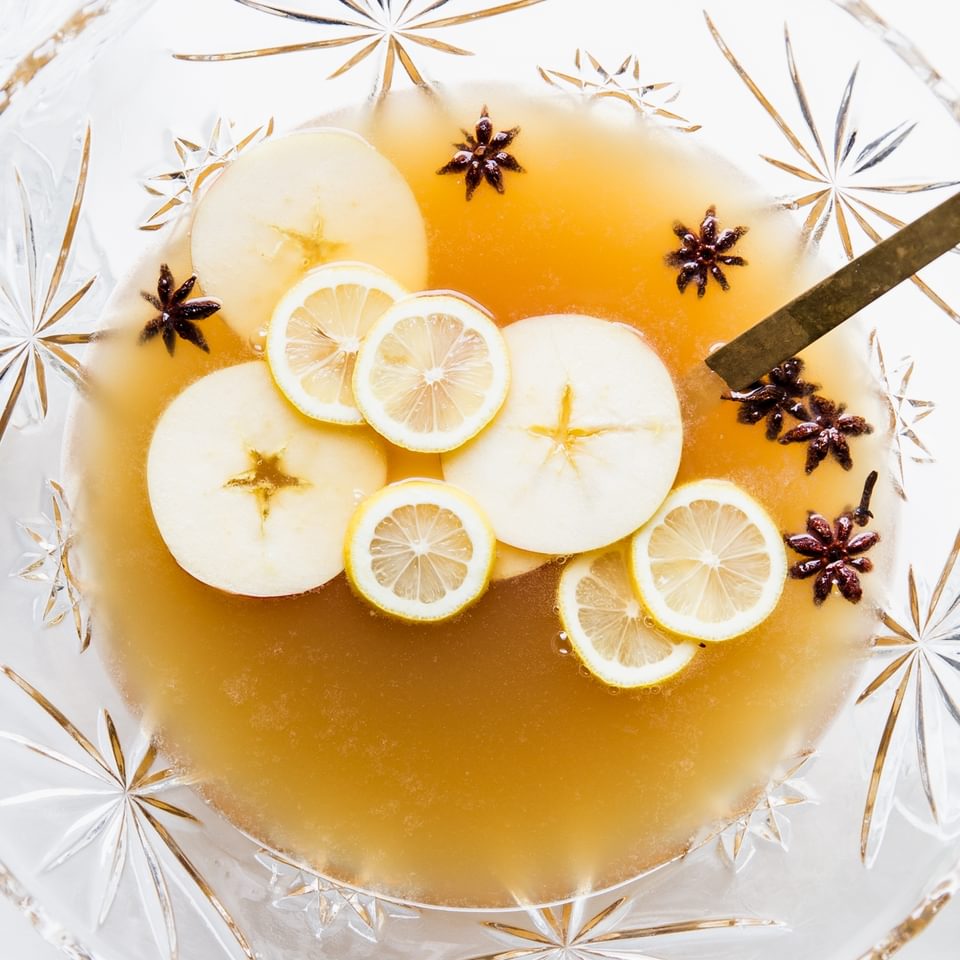 punch bowl filled with spiced bourbon punch, sliced apples, sliced lemons and star anise.