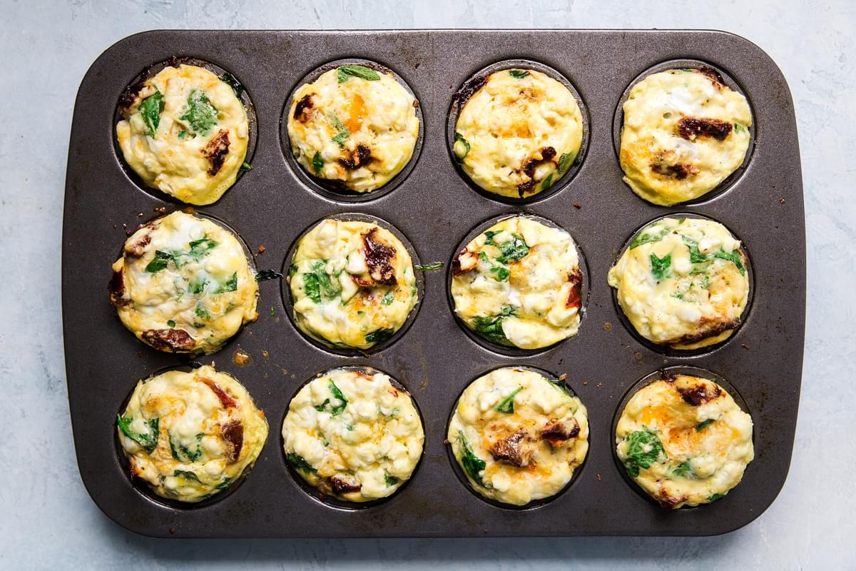 homemade egg cups in a muffin tin made with feta, spinach and sun-dried tomatoes