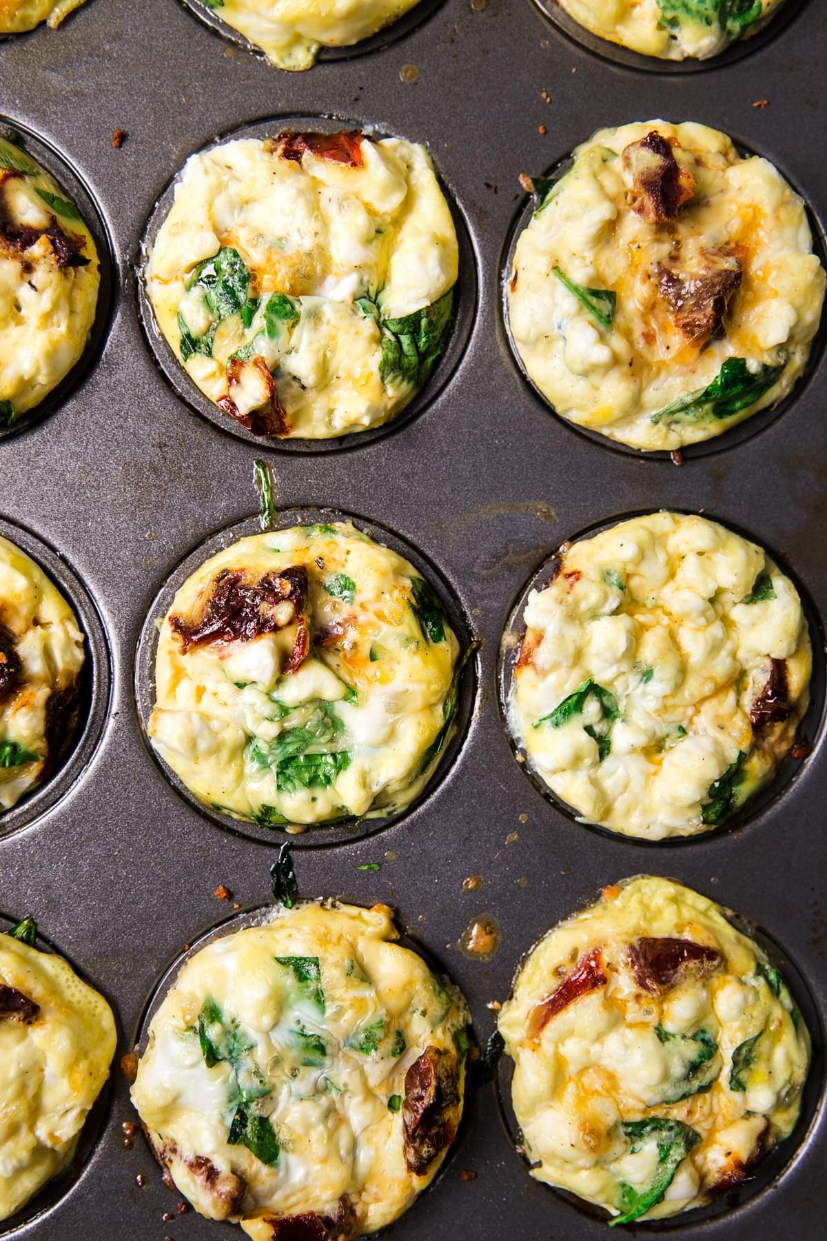 homemade egg cups in a muffin tin made with feta, spinach and sun-dried tomatoes