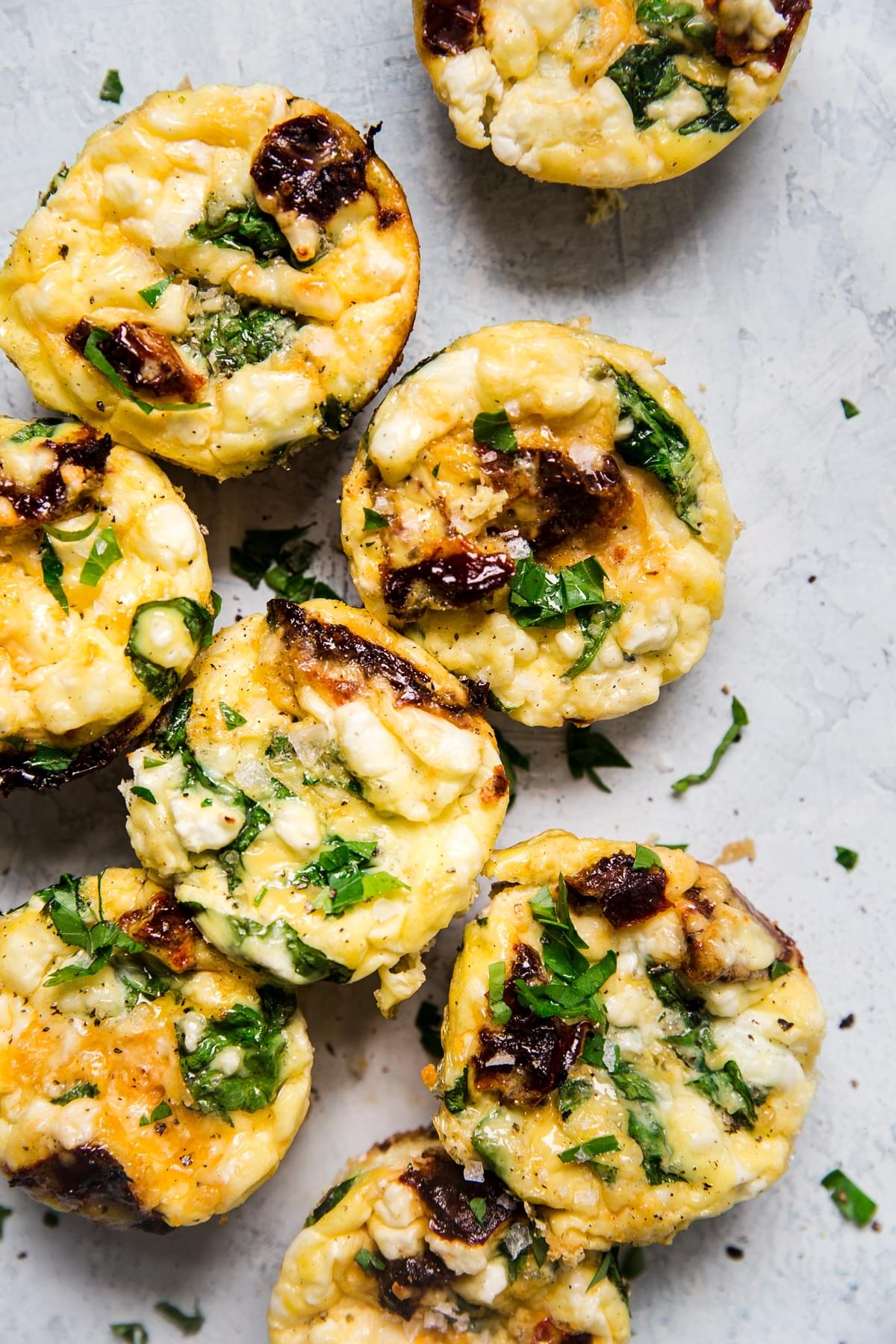 homemade egg cups on a serving board made with feta, spinach and sun-dried tomatoes