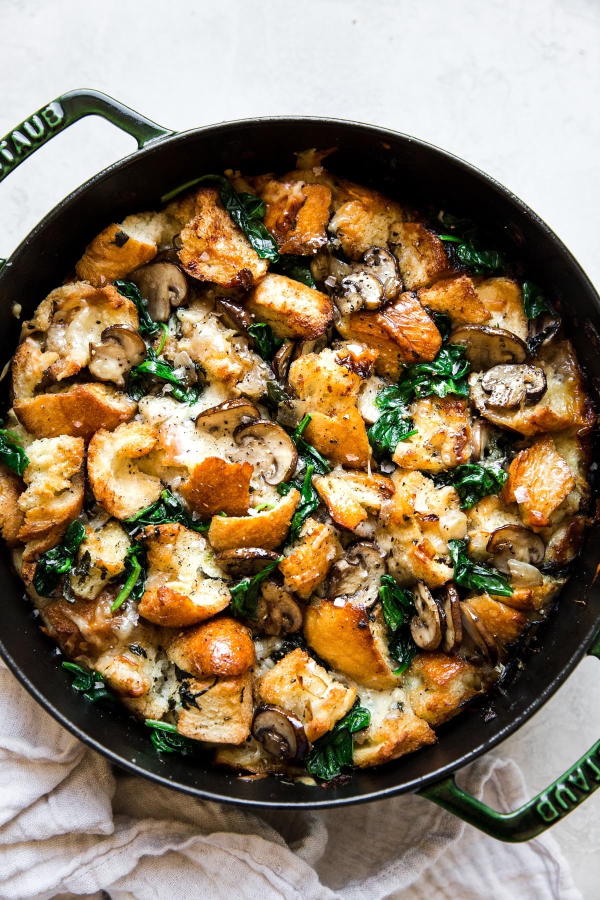 spinach mushroom strata in a green dutch oven with a linen