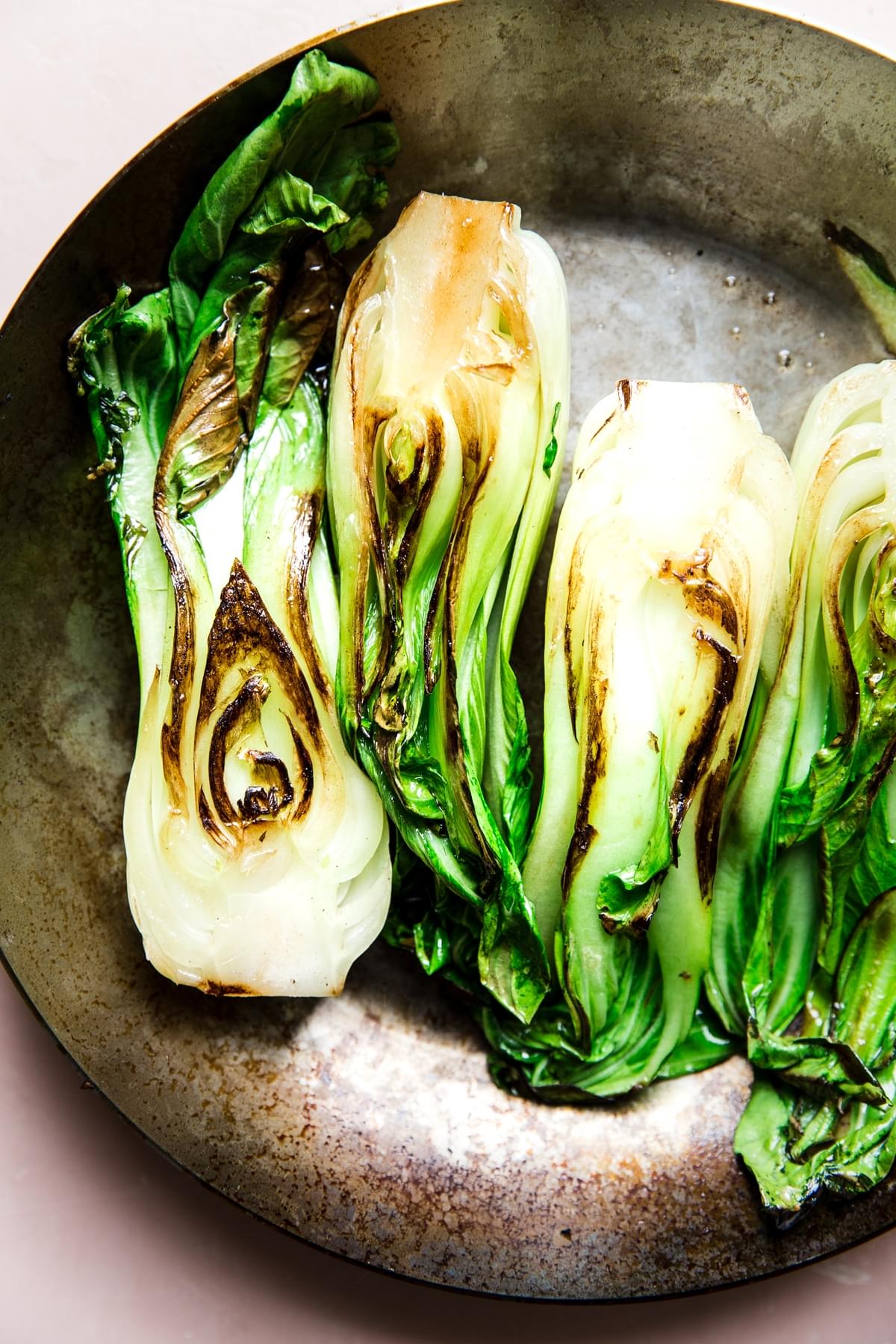 stainless steel skillet with browned bok choy cut in half