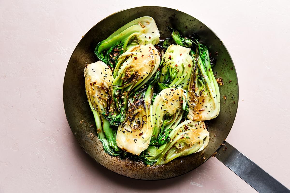 garlic soy sauce mixed with browned bok choy in a skillet