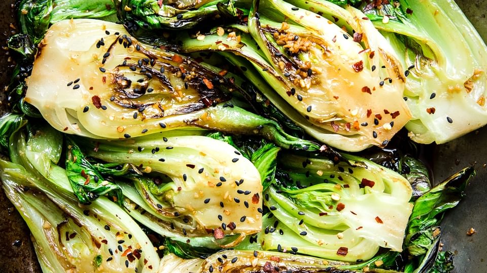 stir fried bok choy with garlic soy sauce and sesame seeds in a skillet