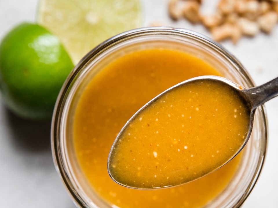 spoon in a glass jar with thai salad dressing