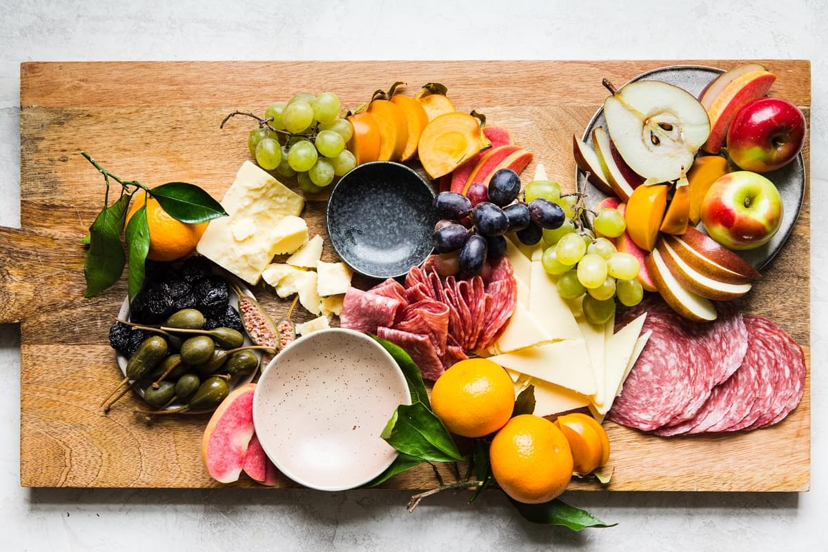 The perfect cheese board with sharp cheddar, salami, apples, olives