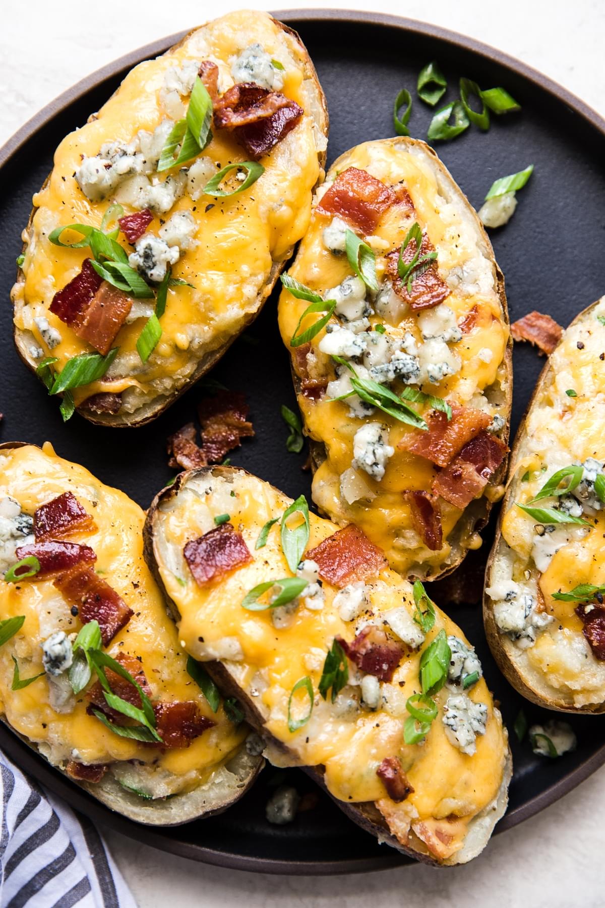 plate of twice baked potatoes topped with melted cheddar cheese, crispy bacon, fresh scallions, and blue cheese