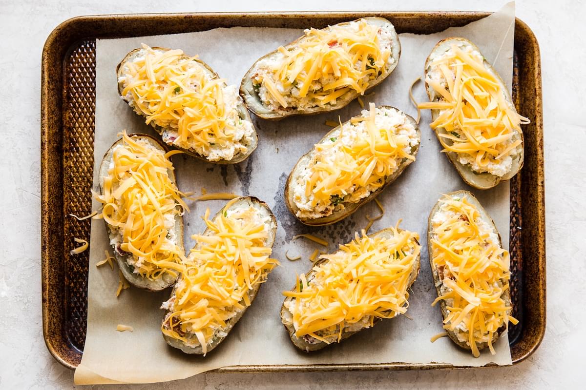 baking sheet of twice baked potatoes topped with yellow cheddar cheese