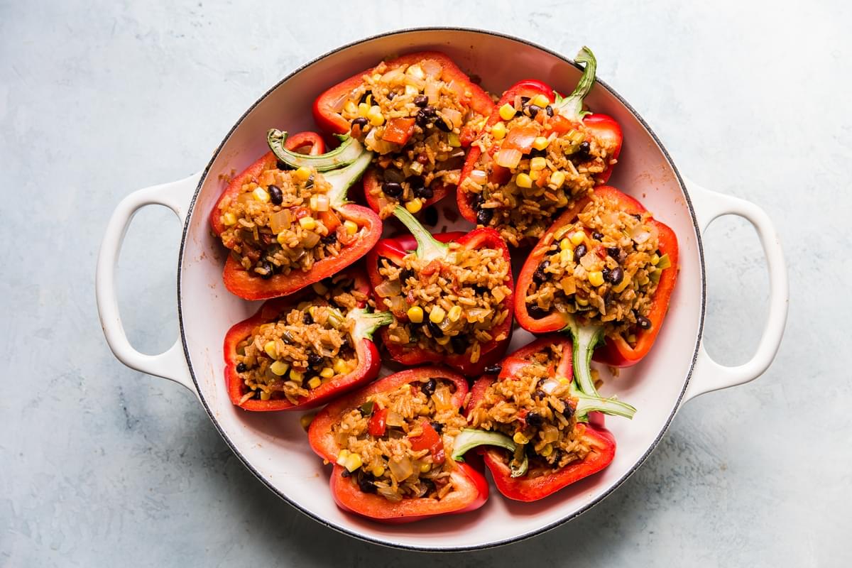 red bell peppers cut in half stuffed with mexican rice in a casserole dish