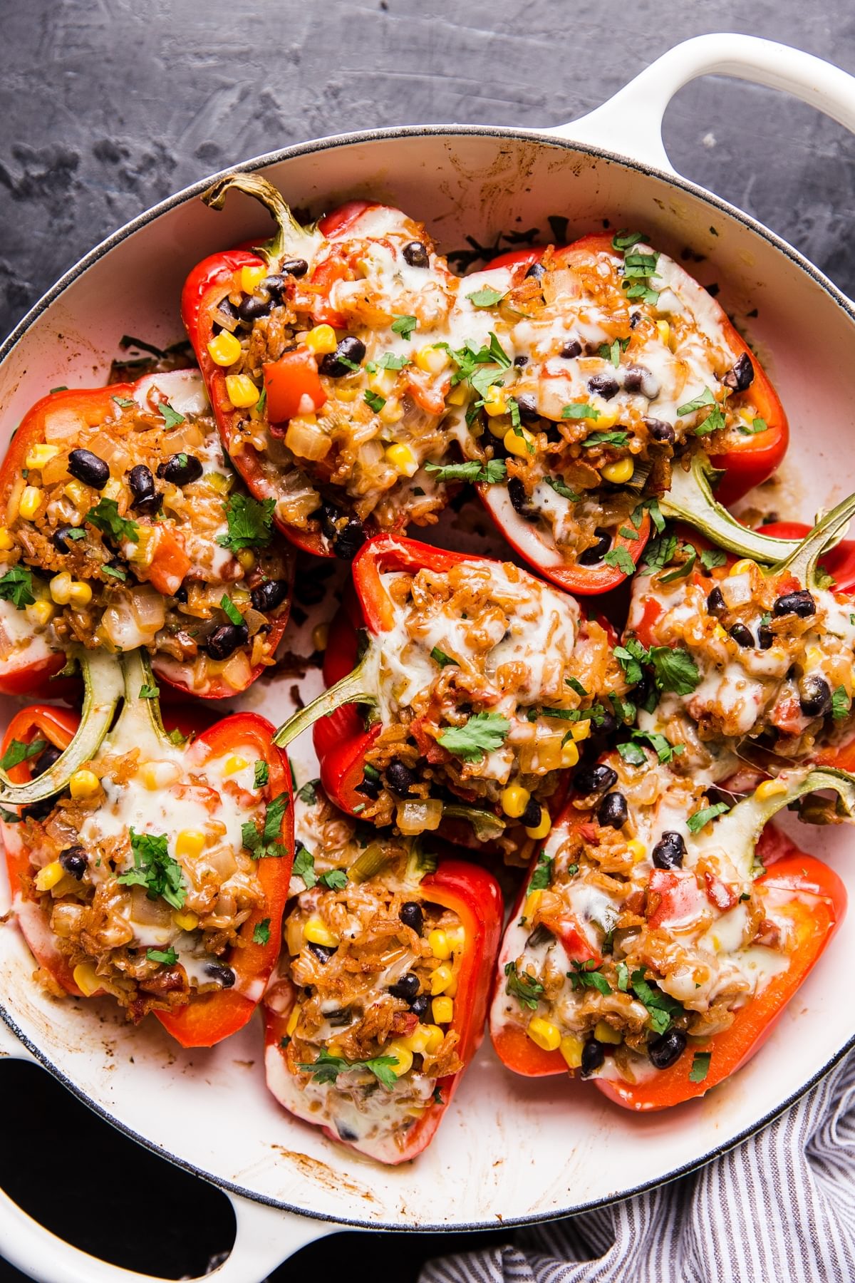 vegetarian stuffed bell peppers topped with cilantro and melted cheese in a casserole