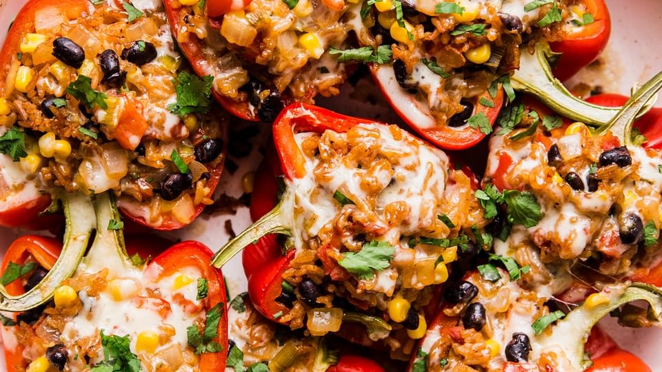 vegetarian stuffed bell peppers topped with cilantro and melted cheese in a casserole