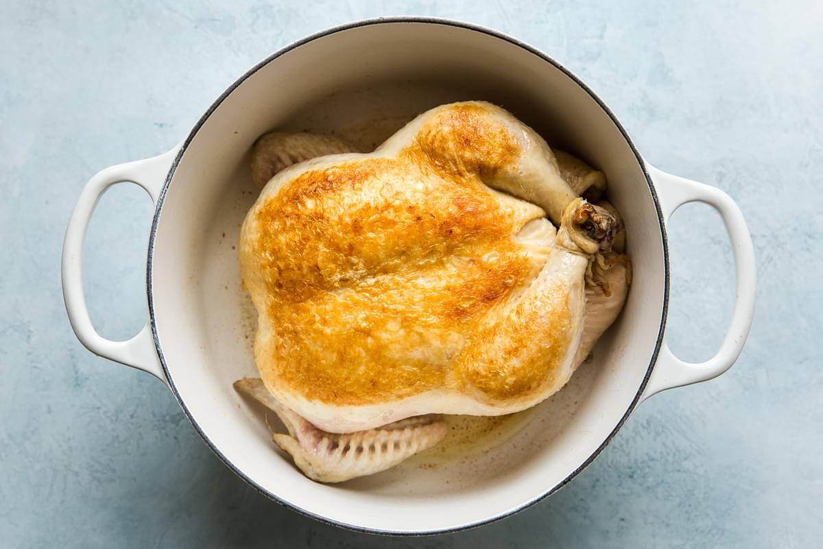 Whole chicken browned in a soup pot