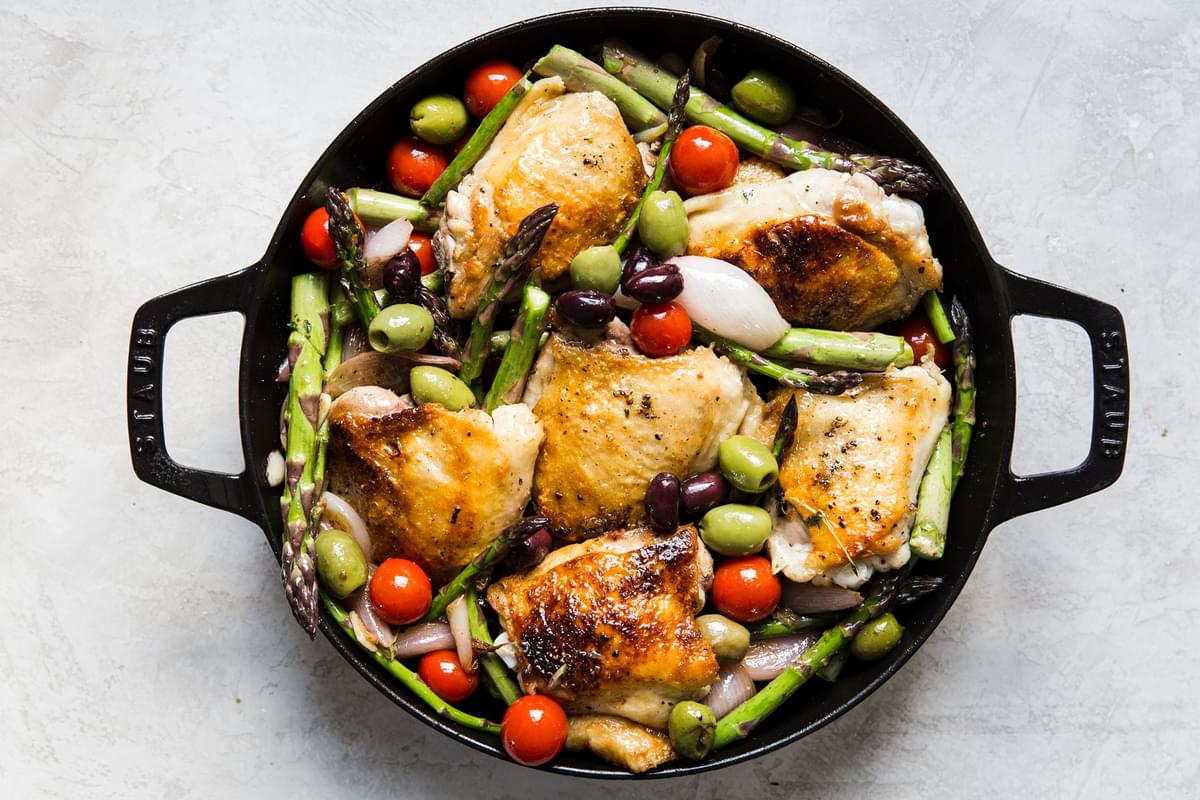 Baked Chicken Thighs With Asparagus, cherry tomatoes, shallots and olives in a white wine dijon sauce.