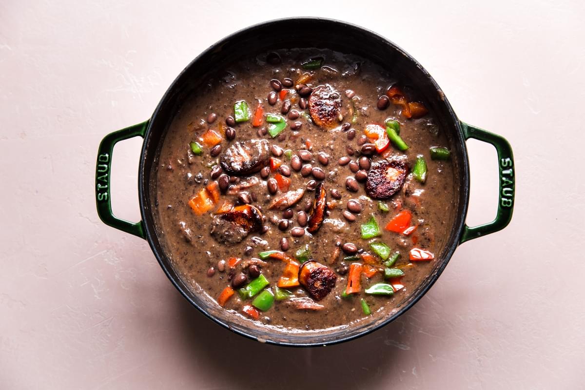 a pot of homemade Black Bean Soup With Smoked Sausage, onion and bell peppers in a pot