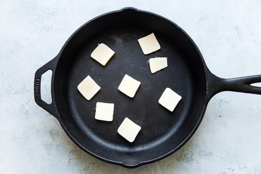 cast iron skillet with piece of butter in it