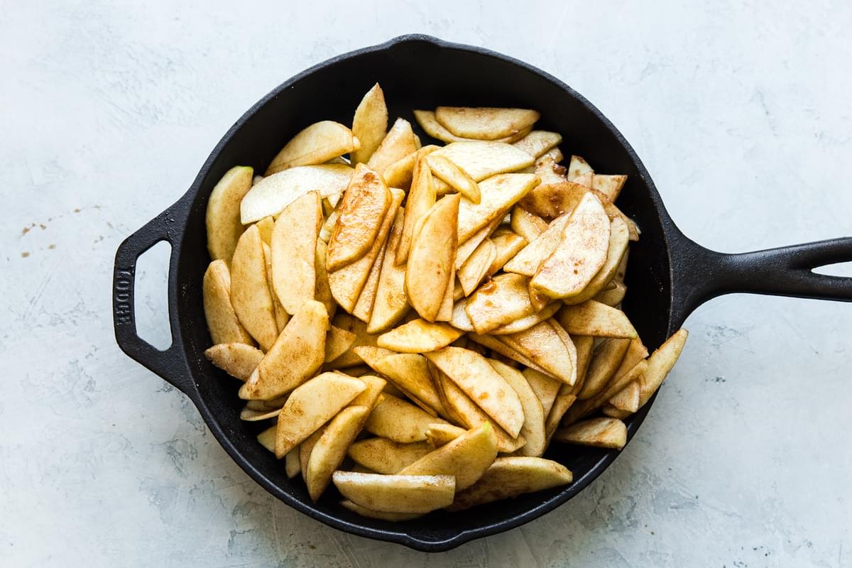 black cast iron skillet filled with spiced apple slices