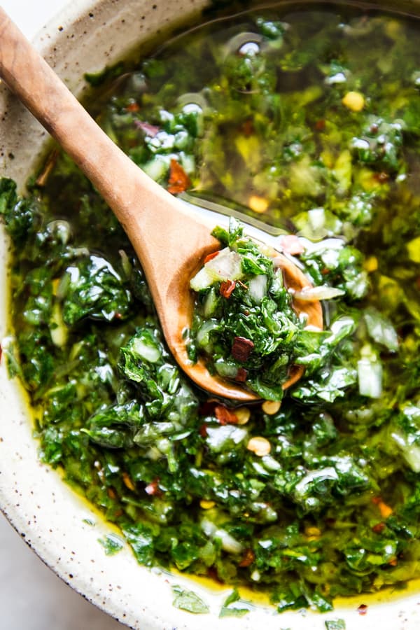 chimichurri in a bowl with a wooden spoon