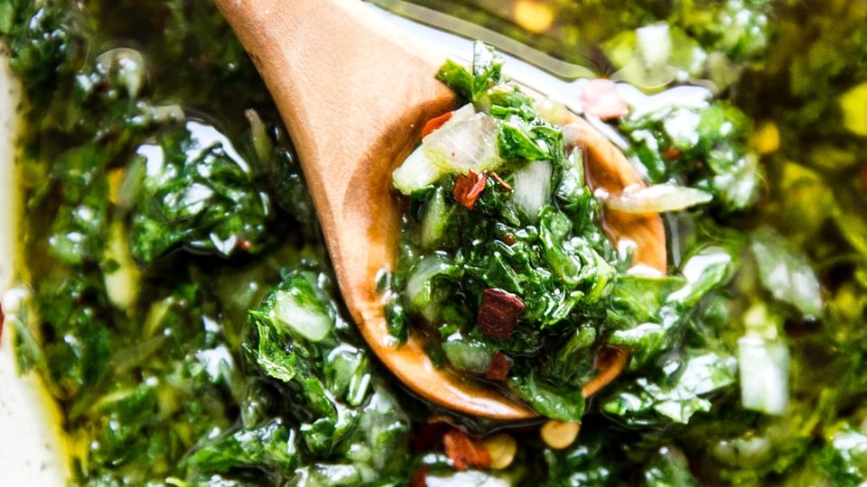 homemade chimichurri recipe in a bowl with a wooden spoon