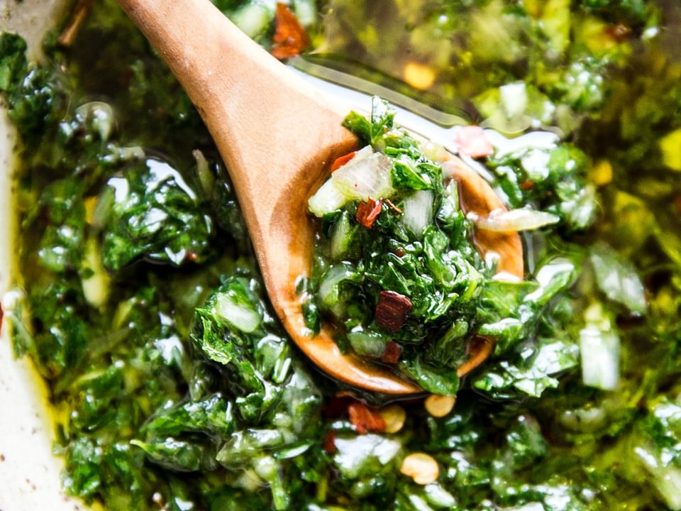 chimichurri in a bowl with a wooden spoon
