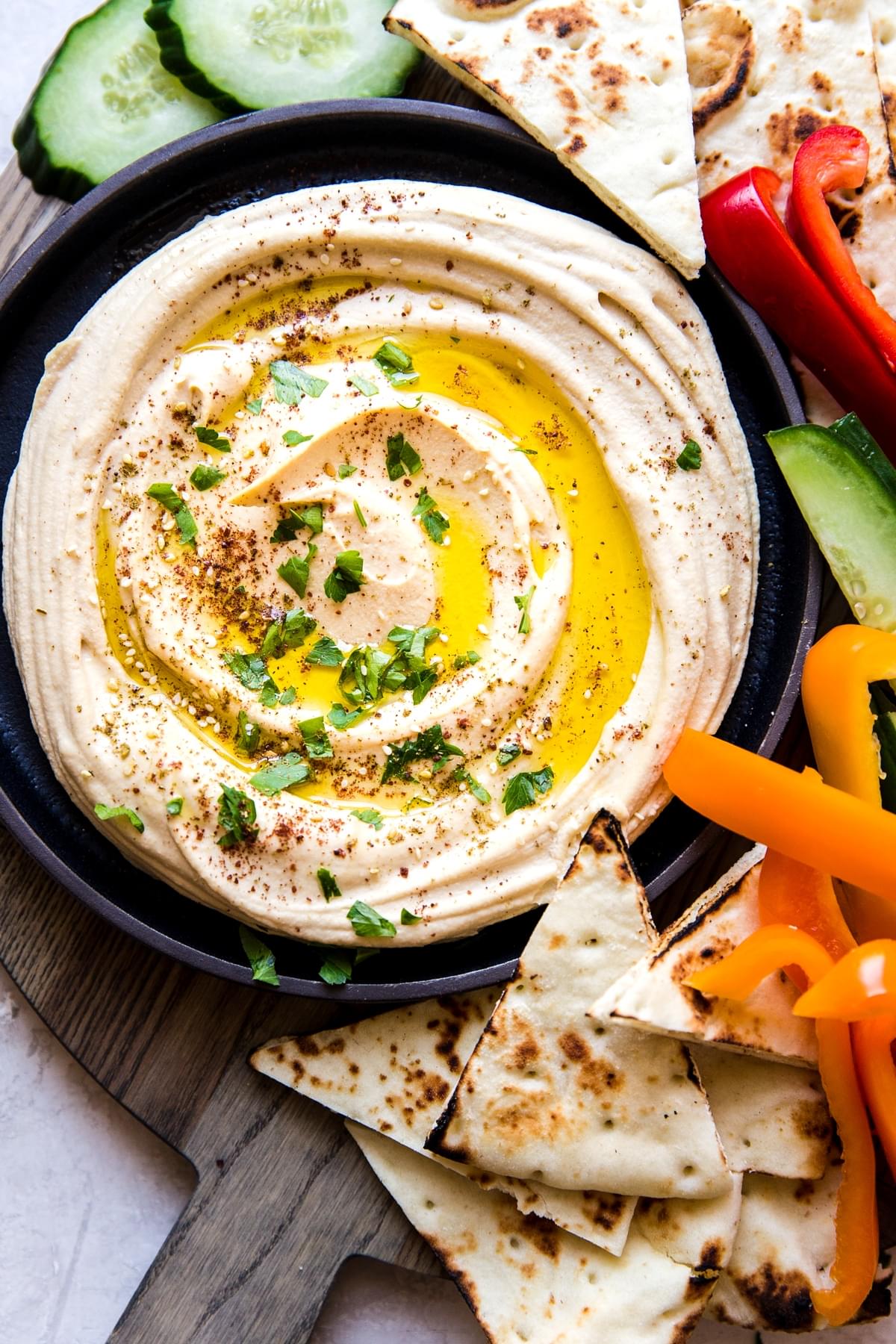 creamy hummus in a bowl served with pita and veggies on a platter
