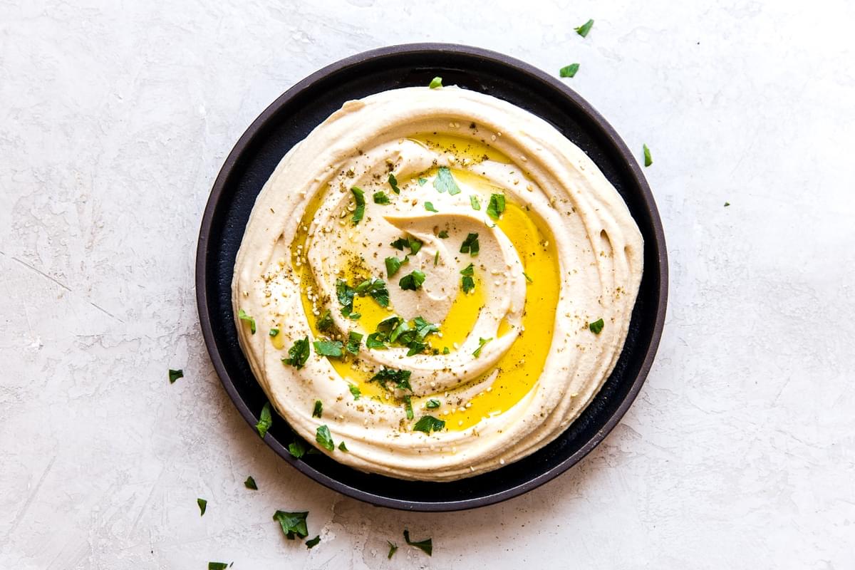 Creamy Classic homemade Hummus in a bowl with olive oil and parsley