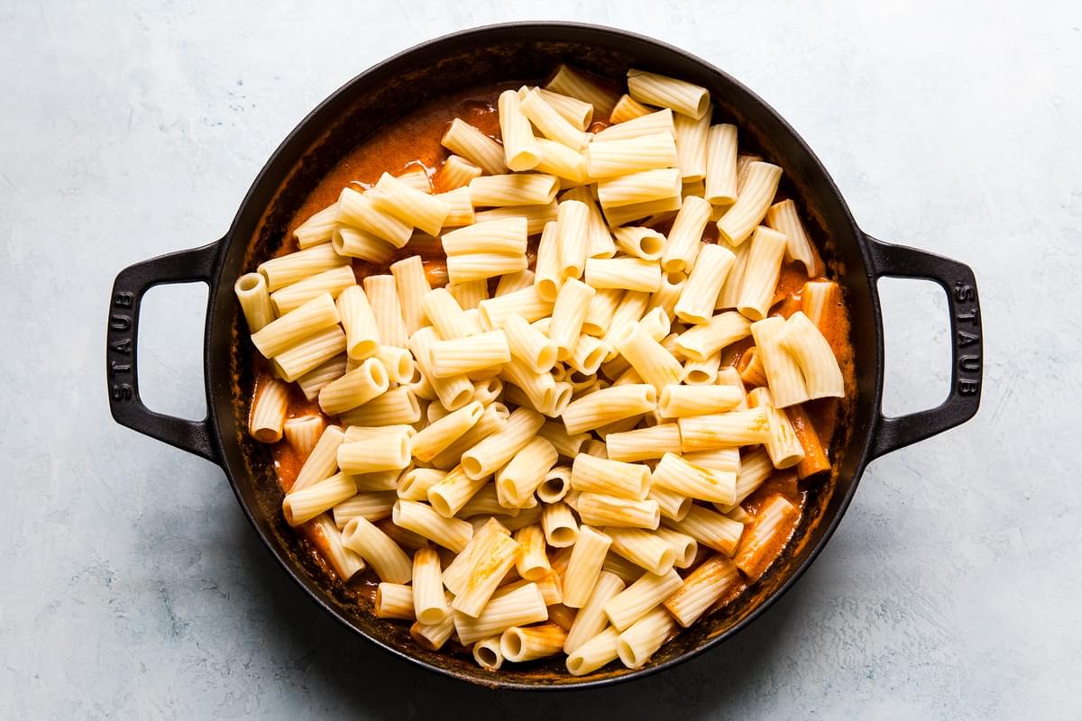 large skillet filled with roasted red pepper sauce and cooked rigatoni pasta