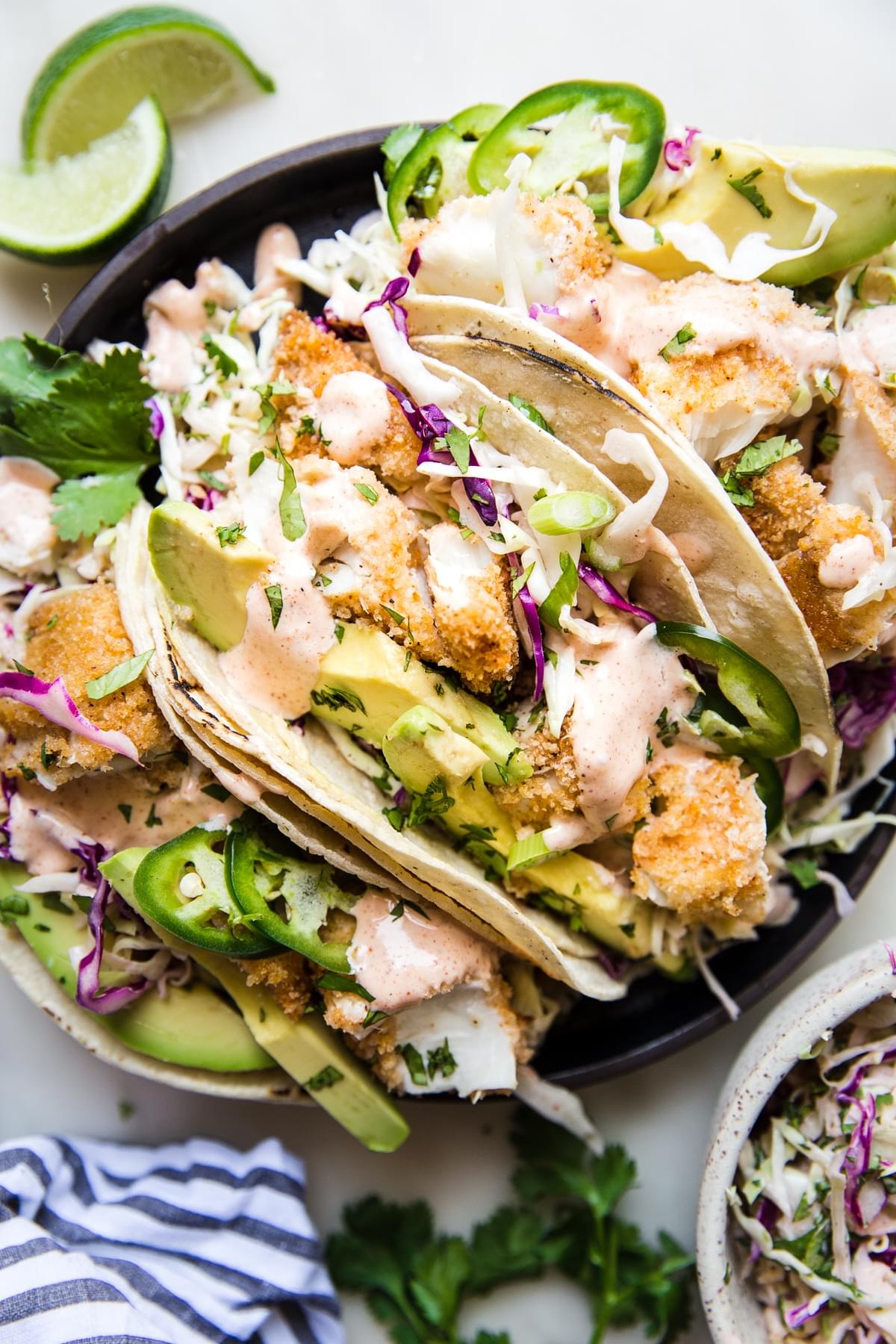 spicy fish tacos with avocado, coleslaw and fresh limes