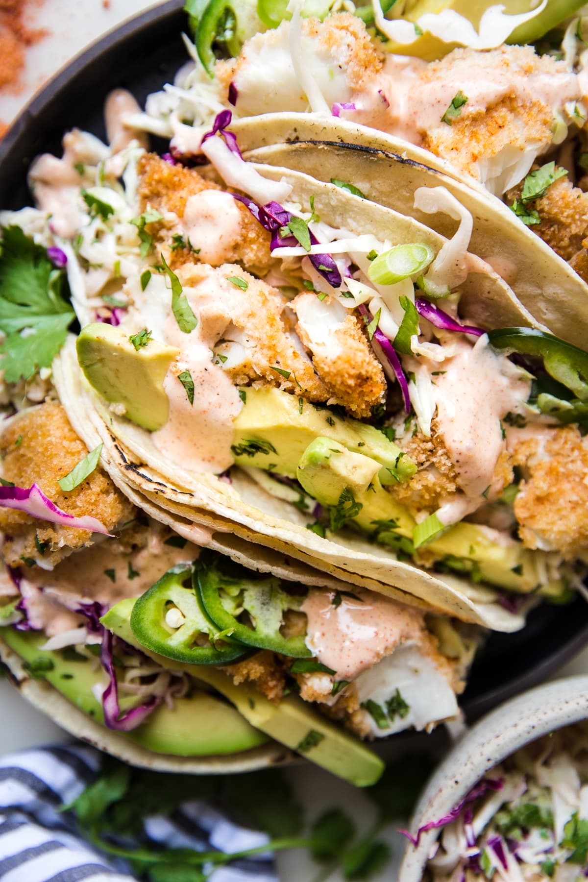 crispy fish tacos topped with cajun sauce, avocado, fresh cilantro and purple cabbage