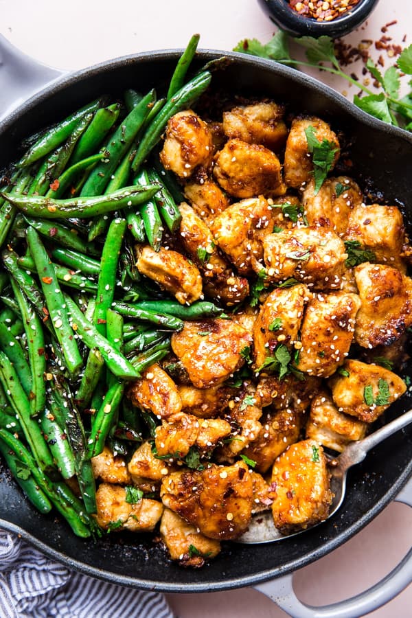 Crispy Chicken Stir Fry With Blistered Green Beans in a skillet with a serving spoon