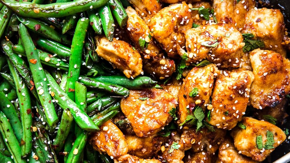 Crispy Chicken Stir Fry With Blistered Green Beans in a skillet with a serving spoon