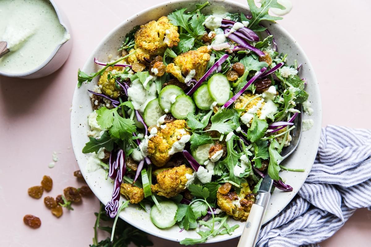 Curried Cauliflower Quinoa Salad with tahini dressing with cucumber and cabbage in a bowl with a fork