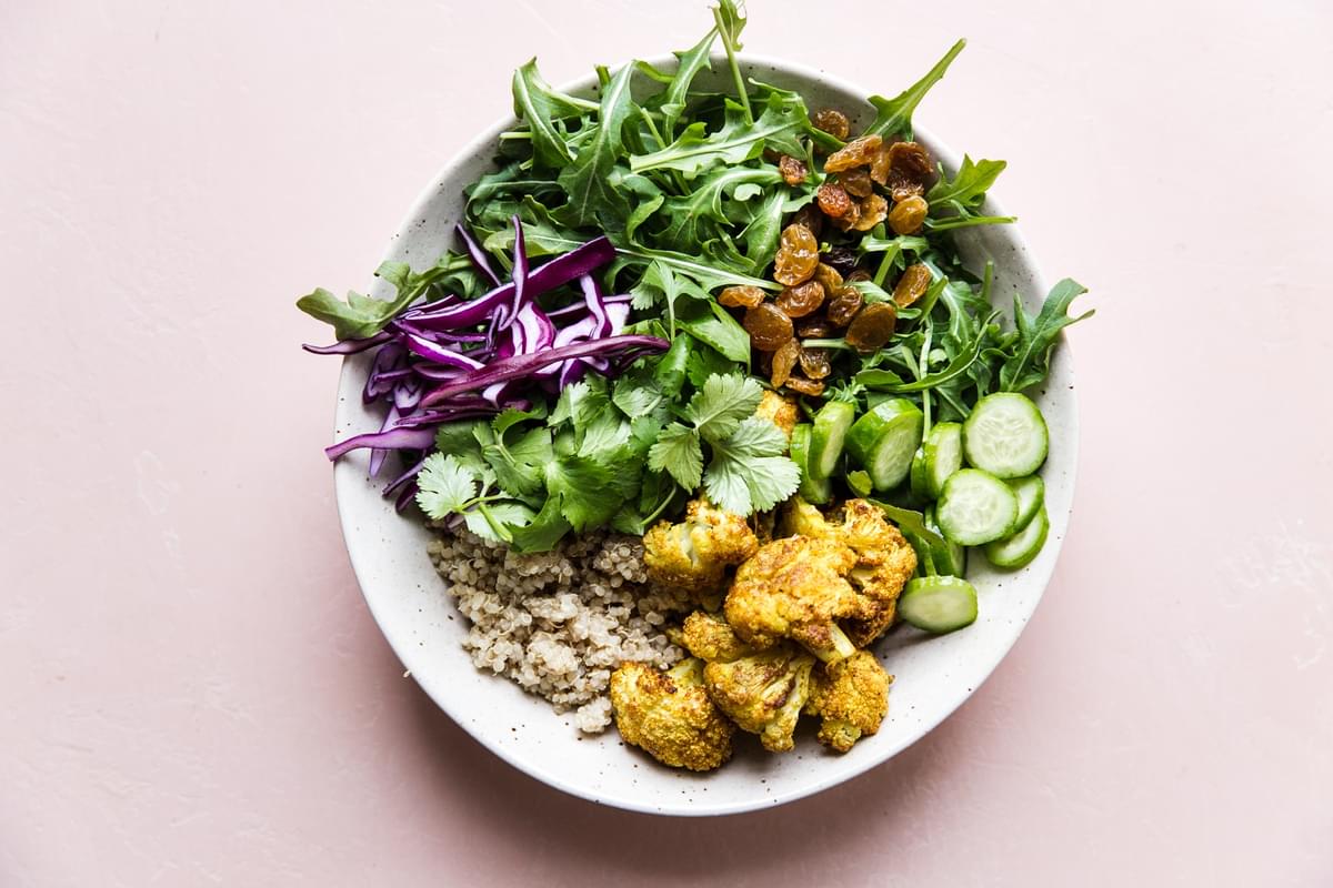 Curried Cauliflower Quinoa Salad with tahini dressing with cucumber and cabbage in a bowl