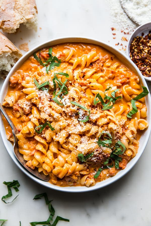 a bowl of pasta tossed with easy vodka sauce sprinkled with red pepper flakes, parmesan cheese and fresh basil