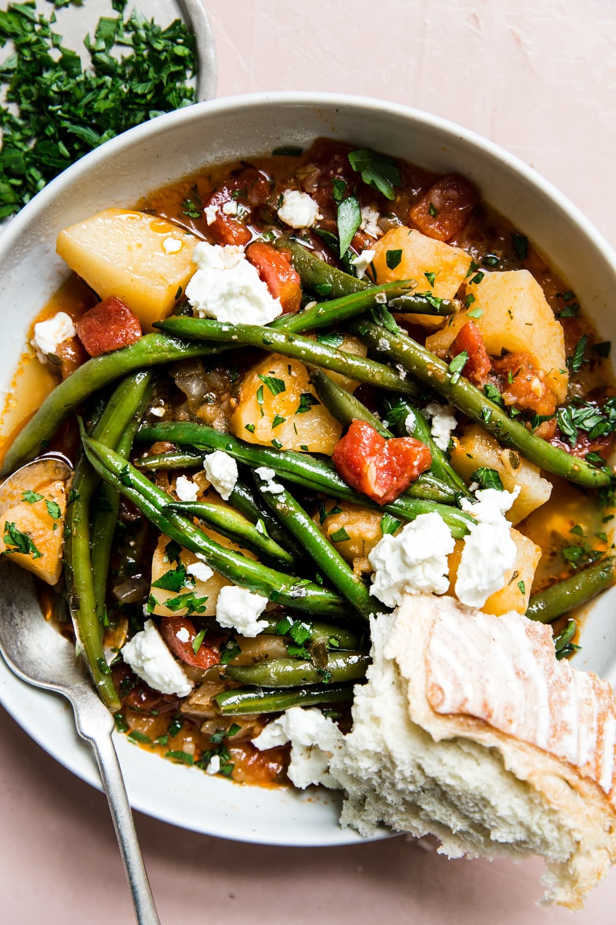 A bowl of fasolakia Greek green beans with feta and crusty bread