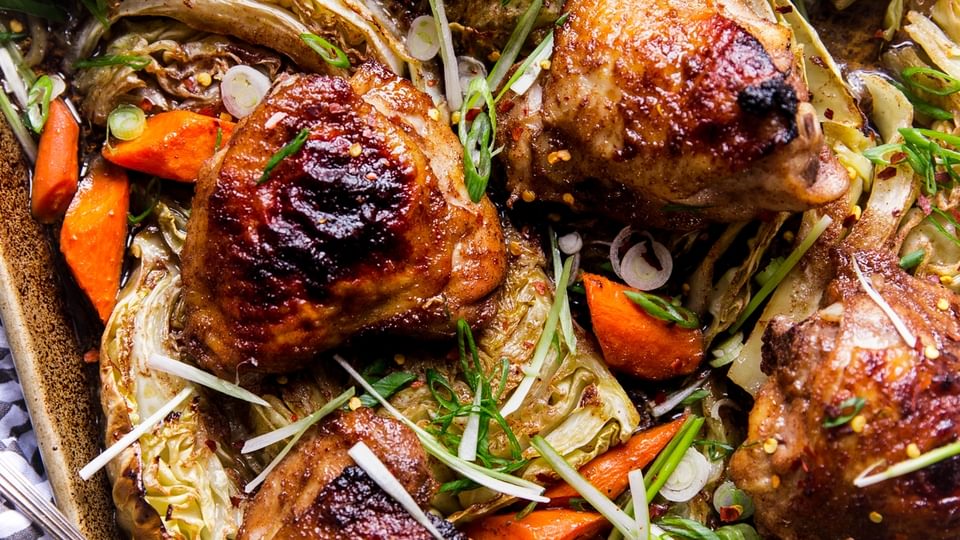 Five Spice Sheet Pan Dinner With Cabbage And Carrots on a baking sheet with a serving spoon