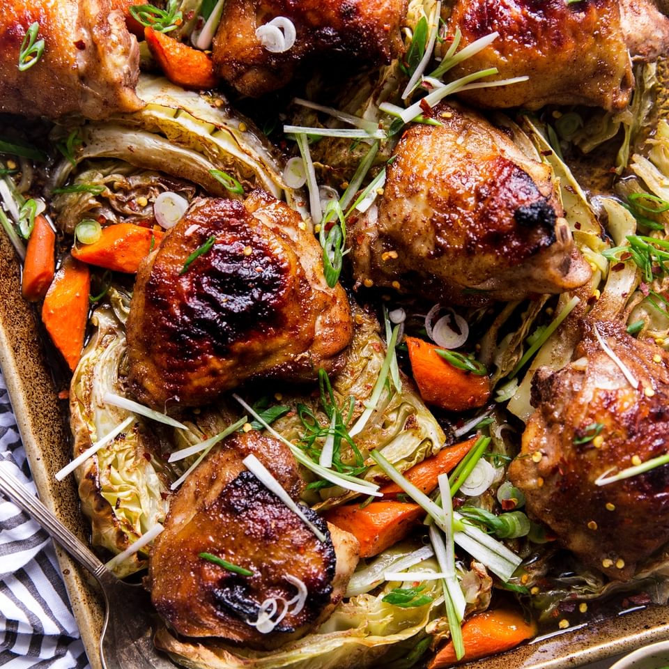 Five Spice Sheet Pan Dinner With Cabbage And Carrots on a baking sheet with a serving spoon