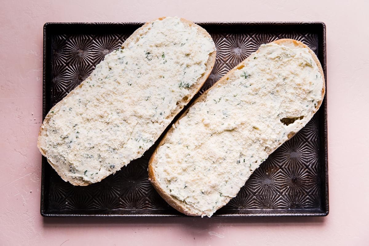 crusty bread loaf cut in half with garlic butter spread on each half