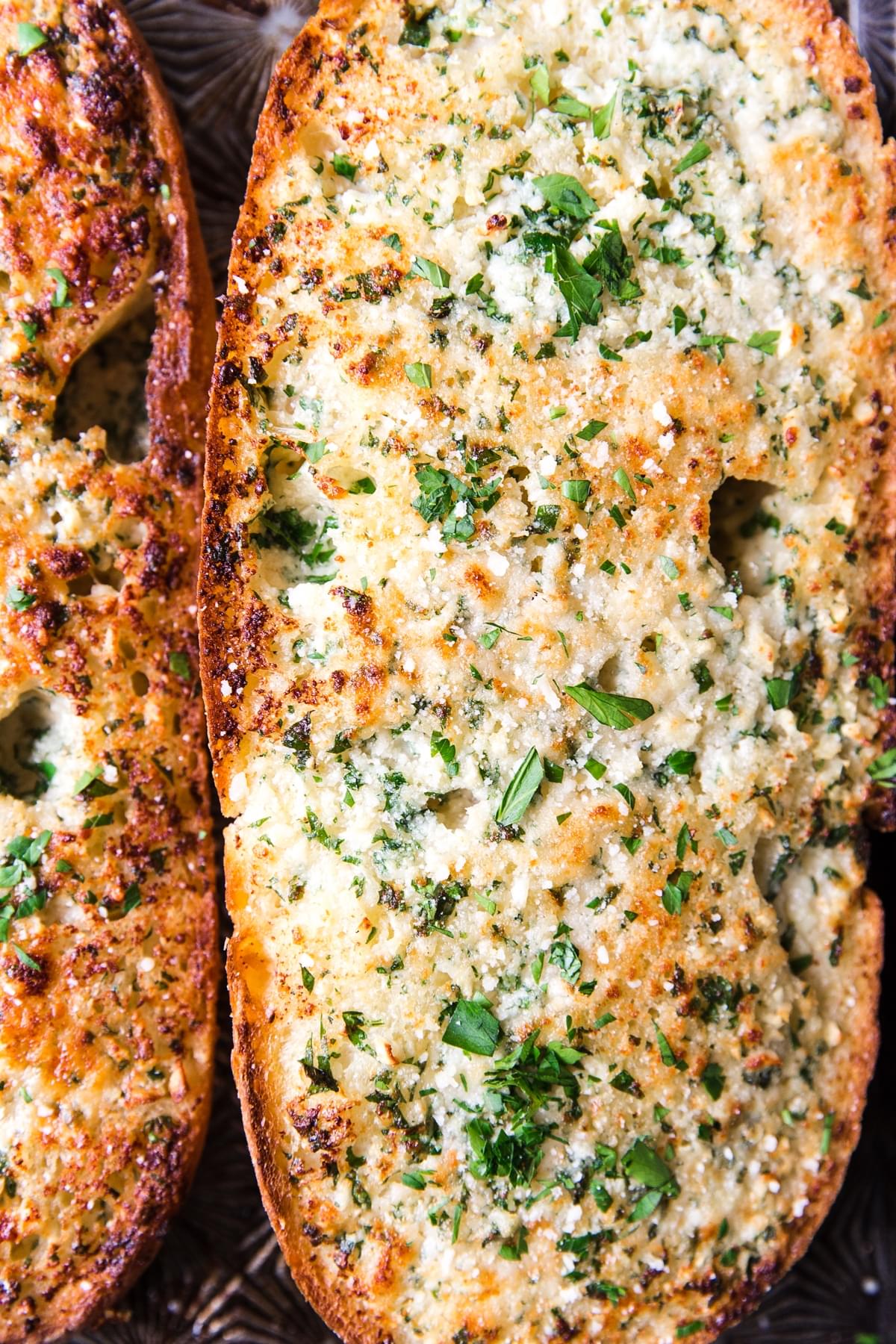 close up of cheesy baked garlic bread topped with fresh parsley