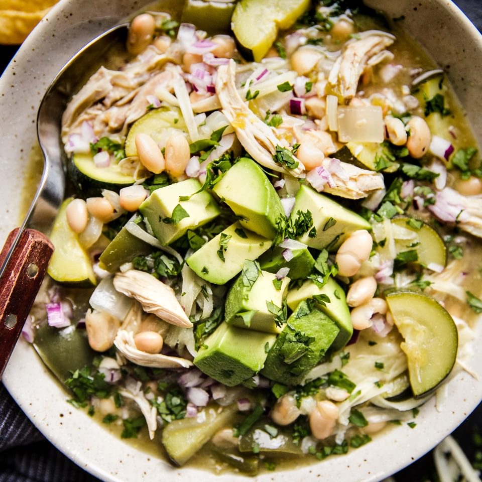 Green Chicken Enchilada Soup recipe with avocado and white beans in a bowl