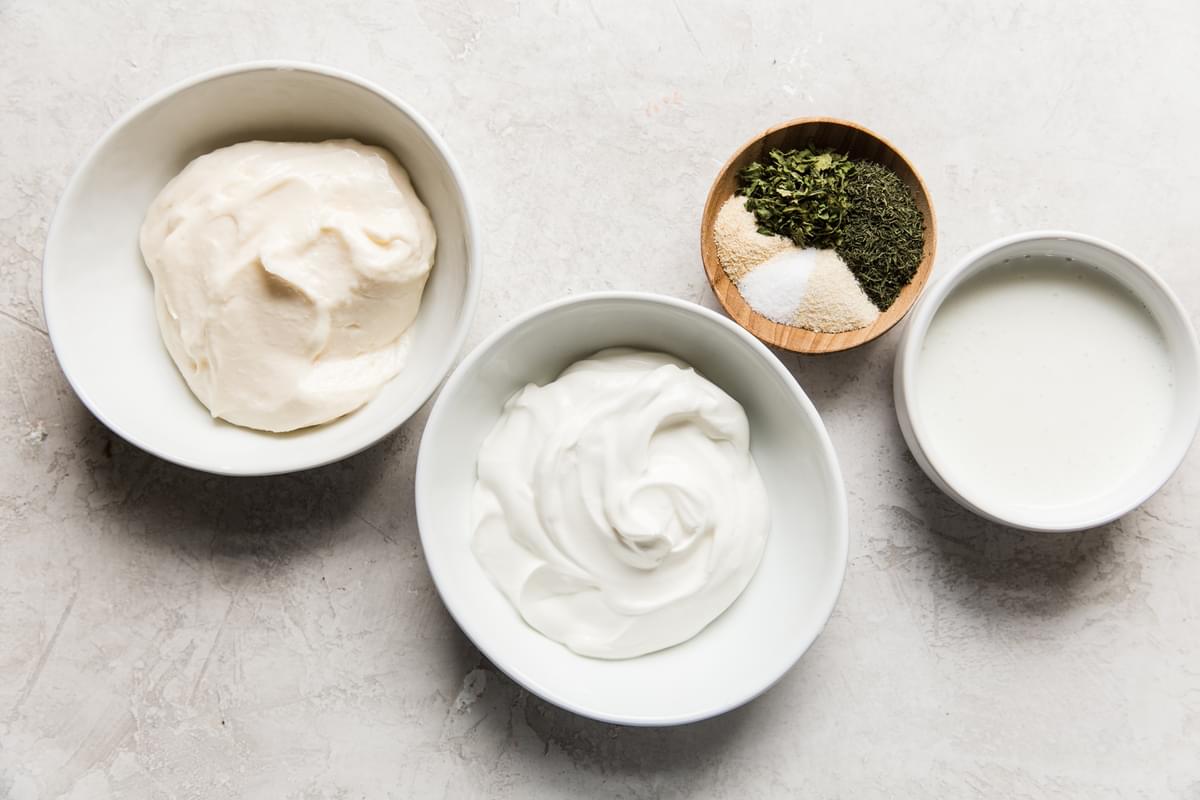 ingredients for homemade ranch dressing; mayonnaise, sour cream, buttermilk, parsley, garlic, salt, onion powder and dill