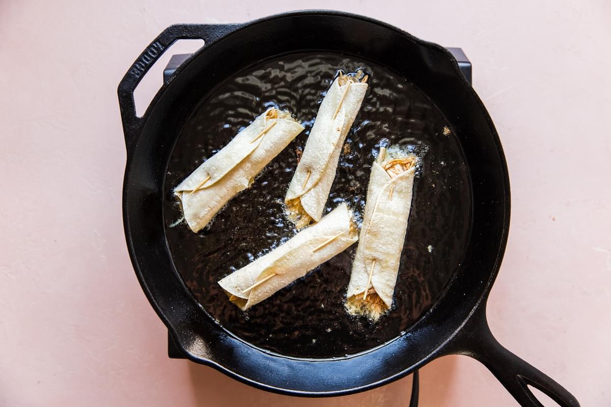 Chicken Taquitos bring fried in a cast iron skillet
