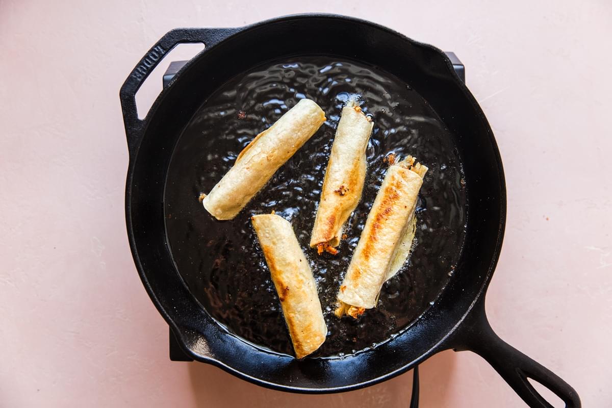 browned Chicken Taquitos in a cast iron pan in canola oil