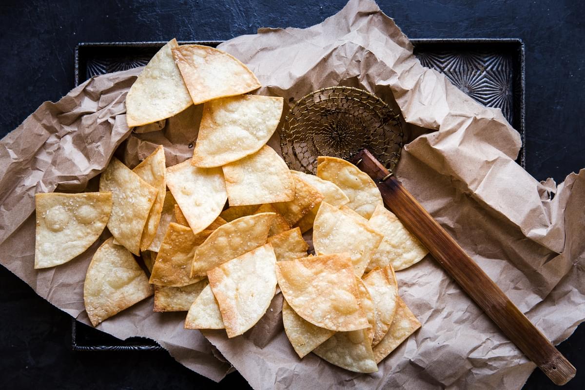 freshly fried corn tortilla chips on parchment paper